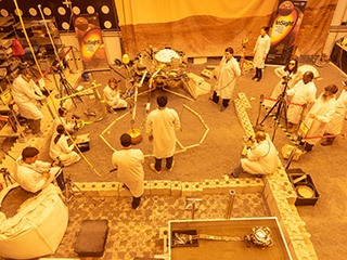 Engineers practice deploying InSight's instruments in a lab at NASA's Jet Propulsion Laboratory in Pasadena, California. Several of them are wearing sunglasses to block the bright yellow lights in the test space, which mimic sunlight as it appears on Mars.