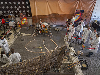 Engineers in Pasadena, California, sculpt a gravel-like material to mimic the terrain in front of NASA's InSight lander on Mars. Recreating the exact conditions will allow them to practice setting down the lander's instruments here on Earth before it's done on Mars.